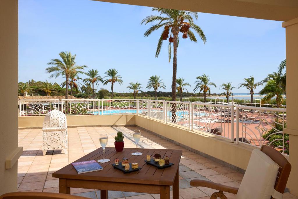 a balcony with a table and a view of a pool at Almar Timi Ama Resort & Spa in Villasimius