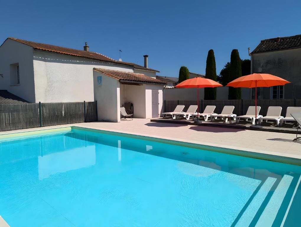 a swimming pool with chairs and umbrellas next to a house at La Bonne Chauffe - Serpentin in Verrières