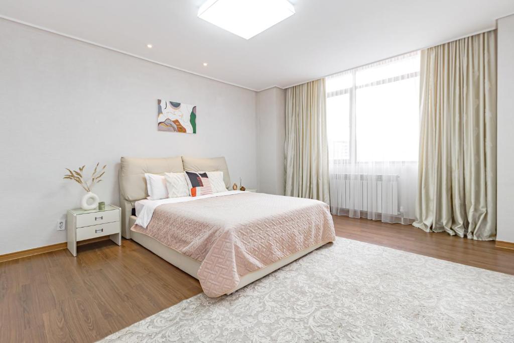 een witte slaapkamer met een bed en een groot raam bij HIGHVILL PARK in Astana