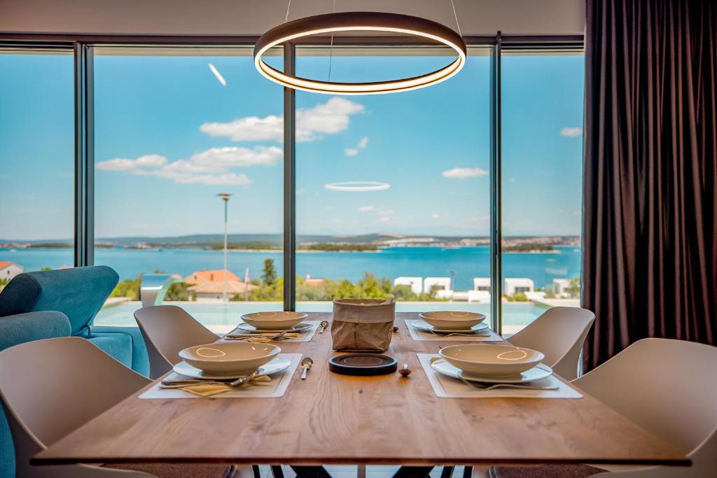 a dining room table with chairs and a large window at Villa View in Ugrinići