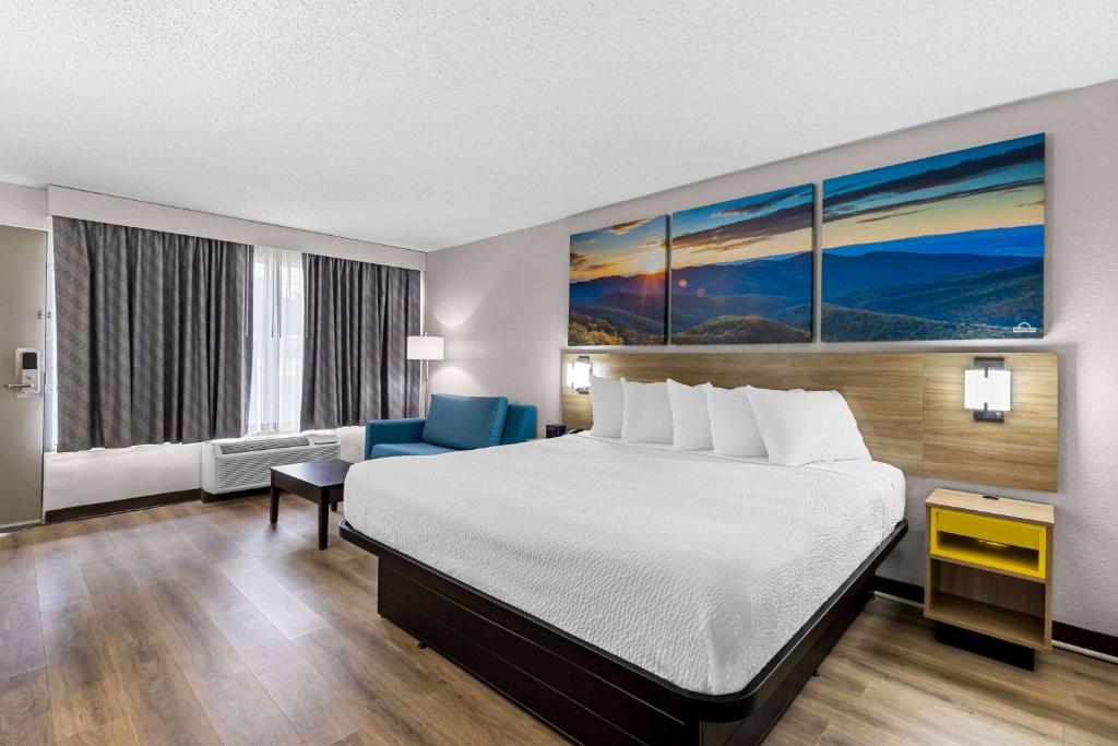 a hotel room with a bed and a blue chair at Days Inn by Wyndham Clayton in Clayton