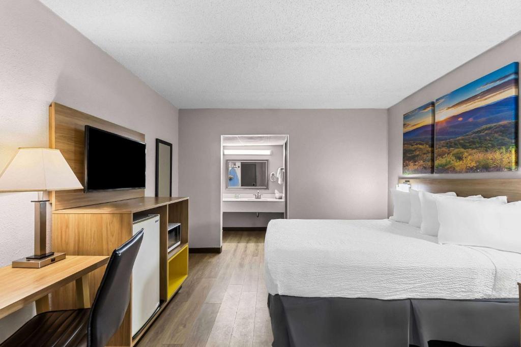 a hotel room with a bed and a desk with a television at Days Inn by Wyndham Clayton in Clayton