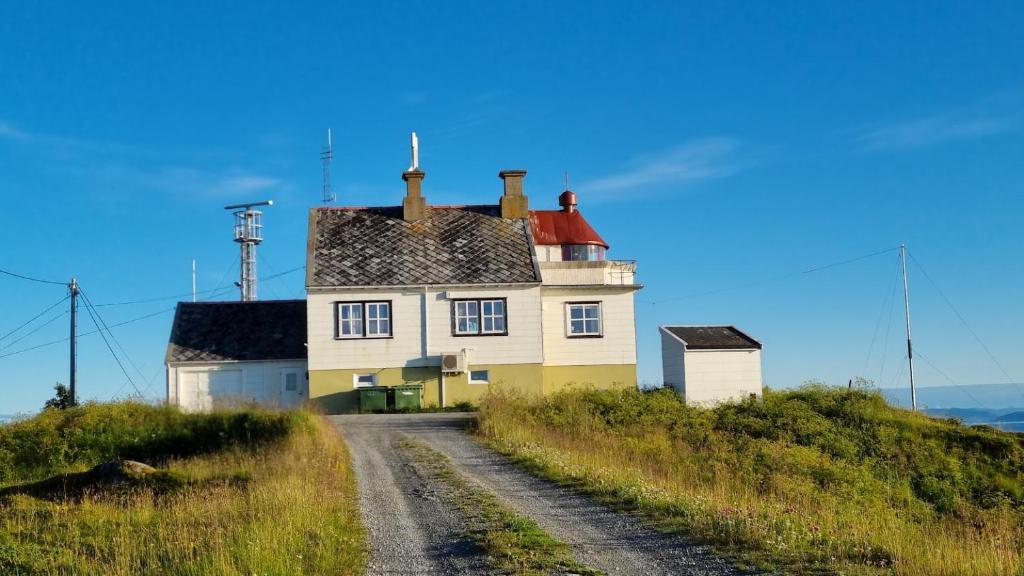 a house on top of a hill with a dirt road at Torsvåg Fyr in Vannareid