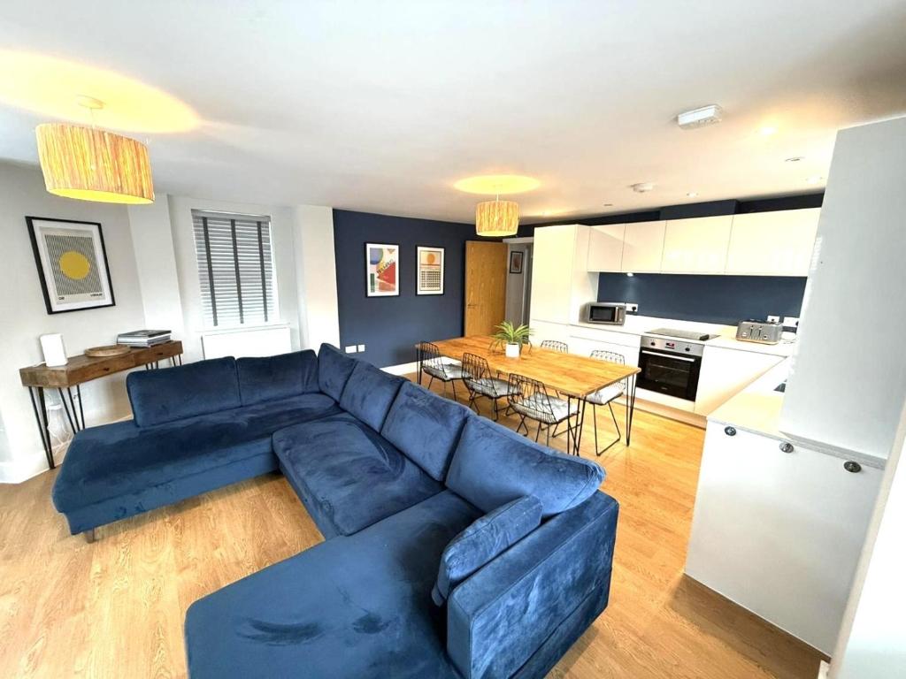 a living room with a blue couch and a kitchen at X-Large two bedroom & two bathroom apartment with free evening parking in Southampton