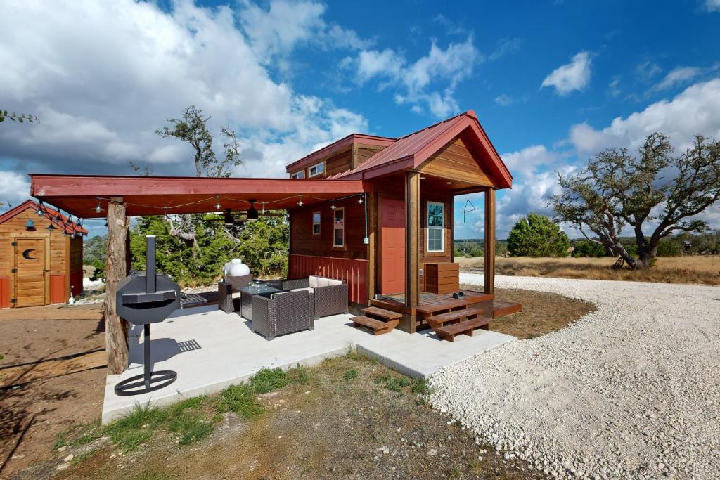a smallshed with a grill and a house at Red Cabin on the Ranch in Harper
