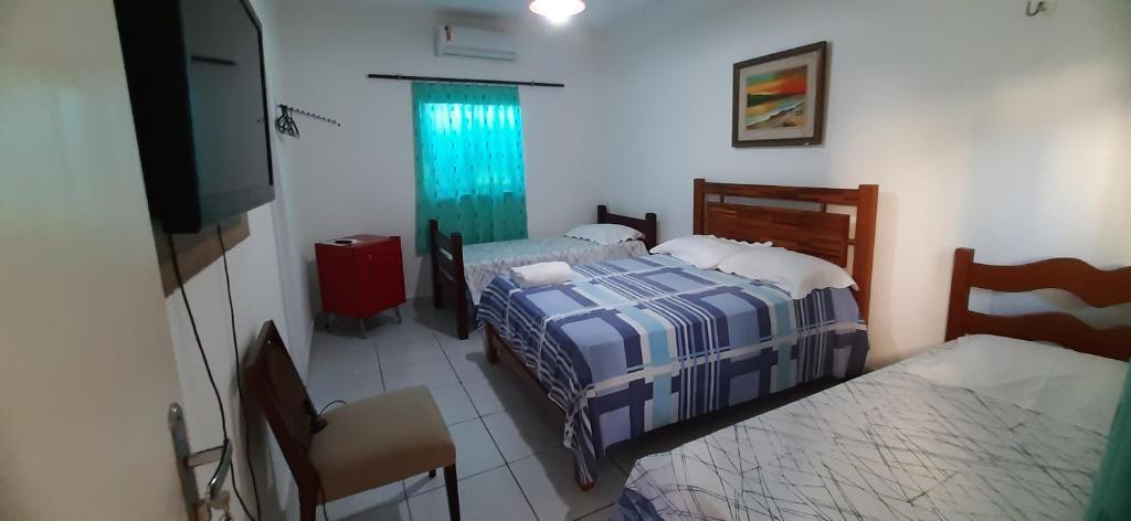 a bedroom with two beds and a flat screen tv at Pousada Casa da Lucinha in Fortaleza