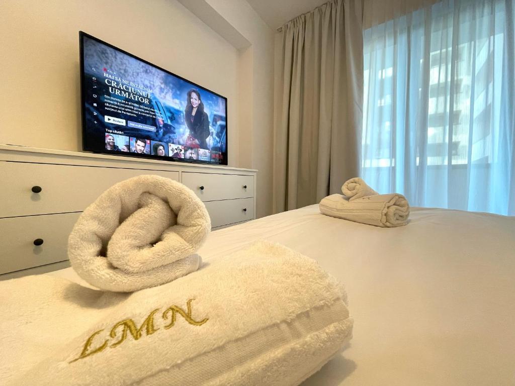 a bedroom with two towels on a bed with a tv at Lumial Mountain Nest in Braşov