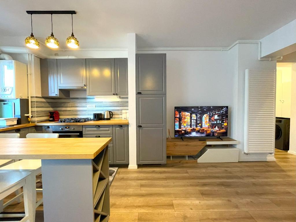 a kitchen with white cabinets and a flat screen tv at Lumial Mountain Nest in Braşov