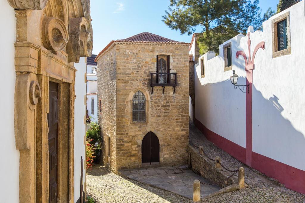 an alleyway with a brick building with a door at Torre de Maneys in Óbidos