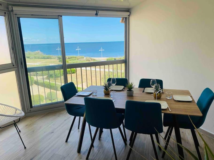 une table et des chaises dans une pièce avec une grande fenêtre dans l'établissement Superbe appart rénové, vue mer, au Cap d'Agde