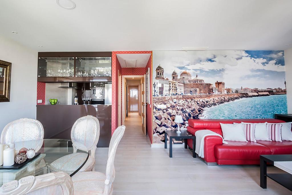 uma sala de estar com um sofá vermelho e uma pintura de uma praia em Apartamento Vistabella em Cádiz