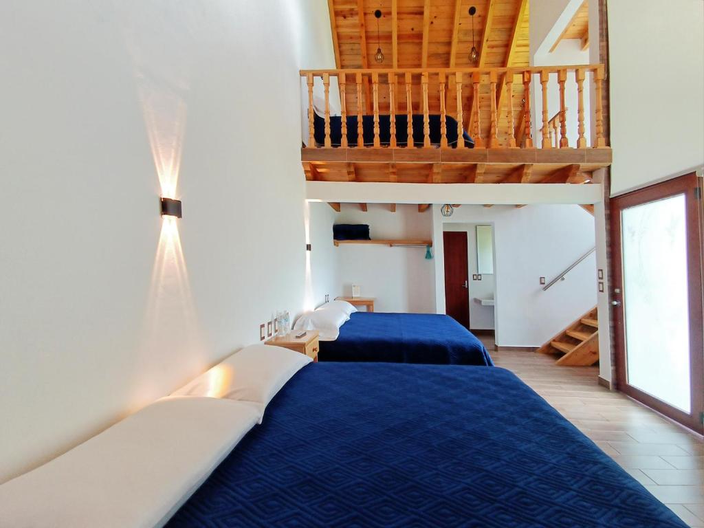 a bedroom with two beds and a staircase at Preciosa Cabaña familiar en Huasca in Huasca de Ocampo