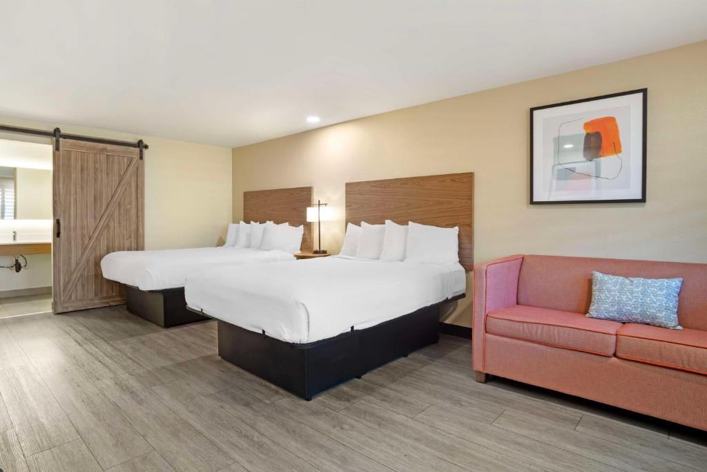 a hotel room with a large bed and a red couch at Best Western Shadow Inn in Woodland