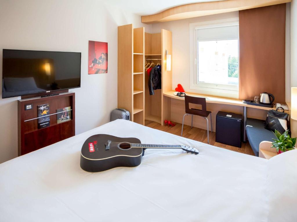 um quarto de hotel com uma guitarra numa cama em Ibis Hotel Plzeň em Plzeň