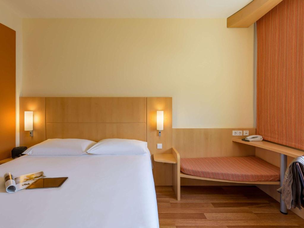a bedroom with a large white bed and a bench at ibis Stuttgart Airport Messe in Leinfelden-Echterdingen