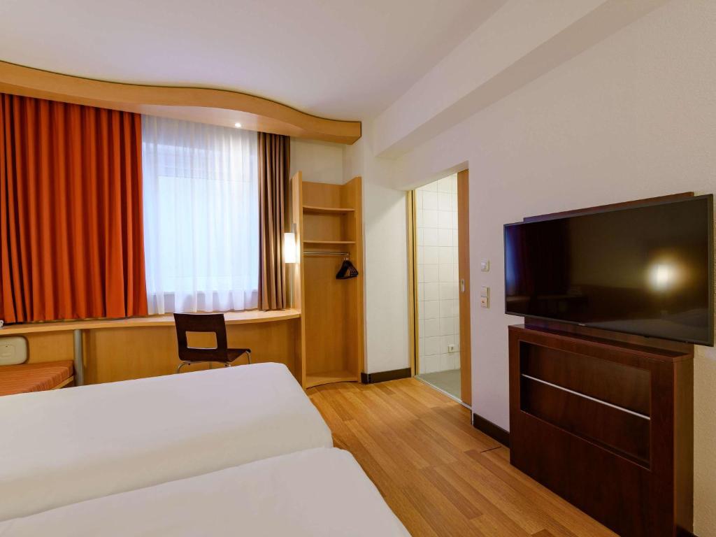 a hotel room with a bed and a flat screen tv at ibis Stuttgart Airport Messe in Leinfelden-Echterdingen