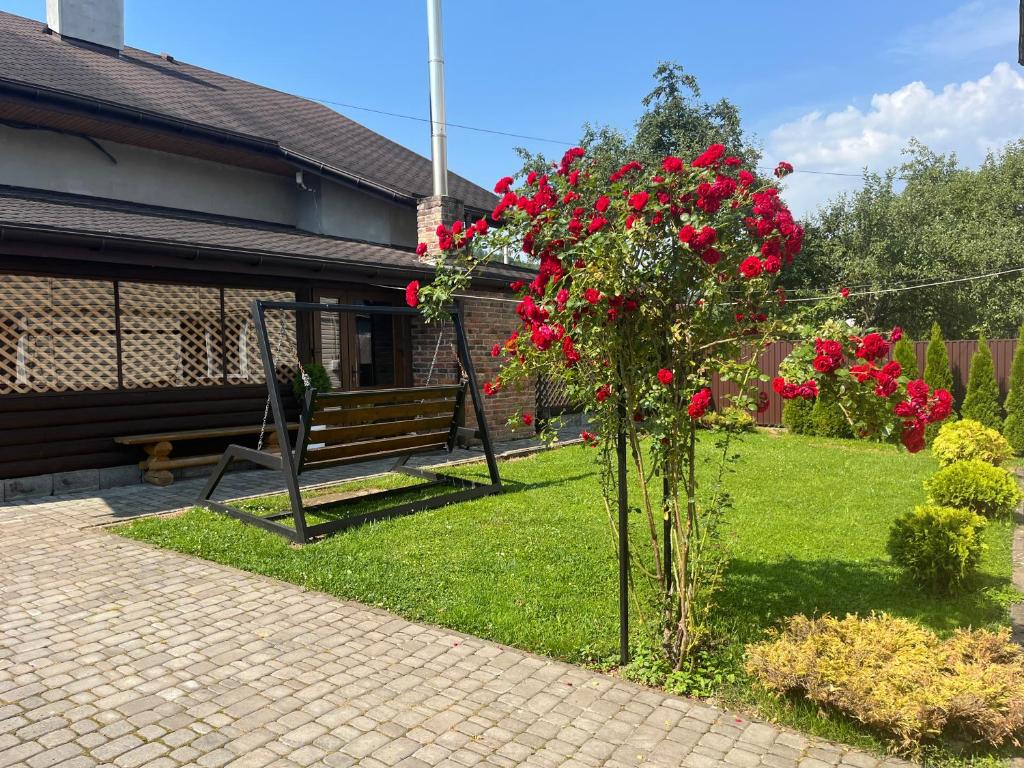 a bush with red flowers next to a bench at Артемів двір in Slavske