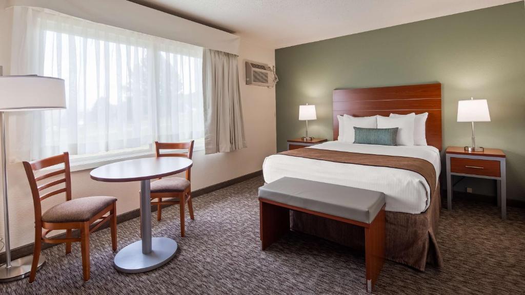 a hotel room with a bed and a table and chairs at Best Western Buffalo Ridge Inn Near Mt Rushmore in Custer