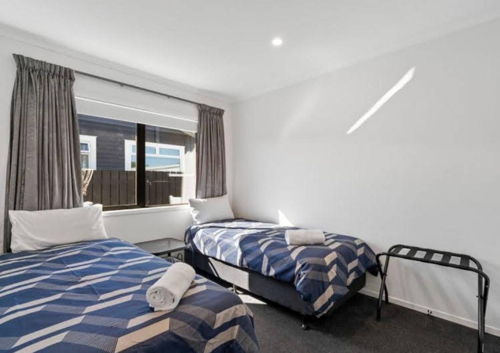 a bedroom with two beds and a window at MiddleIsland-FREE & FAST wifi NETFLIX & aircon in Taupo