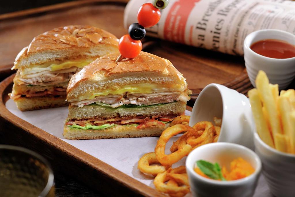 a sandwich on a wooden tray with fries and ketchup at DoubleTree by Hilton Gurgaon New Delhi NCR in Gurgaon