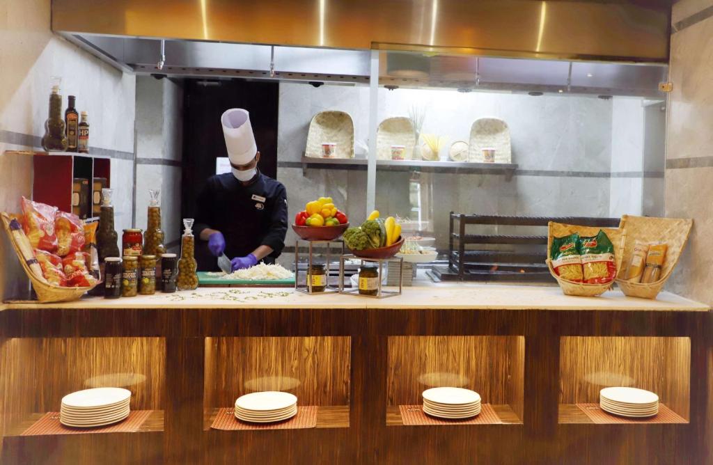 a chef preparing food in a restaurant kitchen at DoubleTree by Hilton Gurgaon New Delhi NCR in Gurgaon