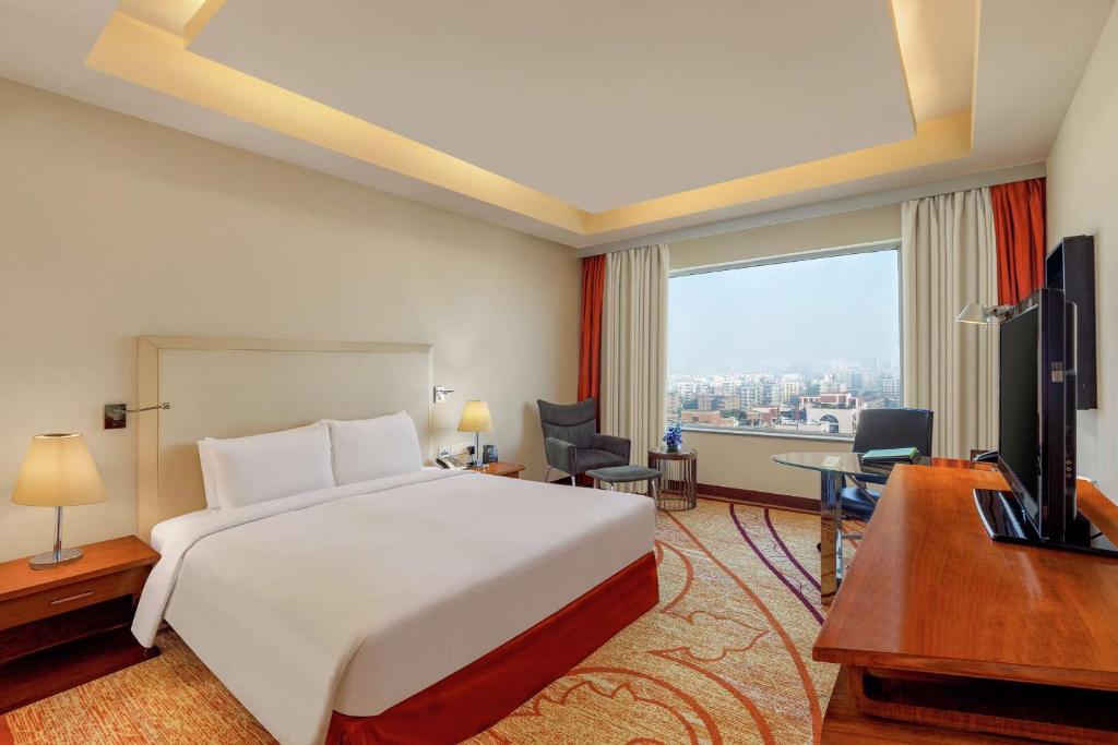 a hotel room with a bed and a desk and a television at DoubleTree by Hilton Gurgaon New Delhi NCR in Gurgaon