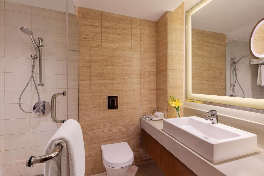 a bathroom with a sink and a toilet and a mirror at DoubleTree by Hilton Gurgaon New Delhi NCR in Gurgaon