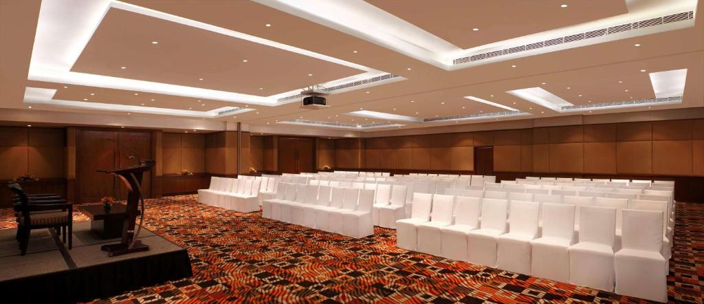 a conference room with white chairs and a podium at DoubleTree by Hilton Gurgaon New Delhi NCR in Gurgaon