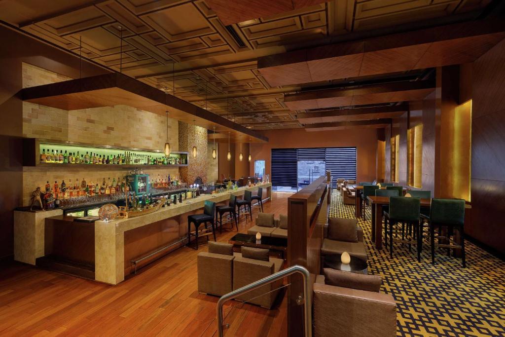 a restaurant with a bar with chairs and tables at DoubleTree by Hilton Gurgaon New Delhi NCR in Gurgaon