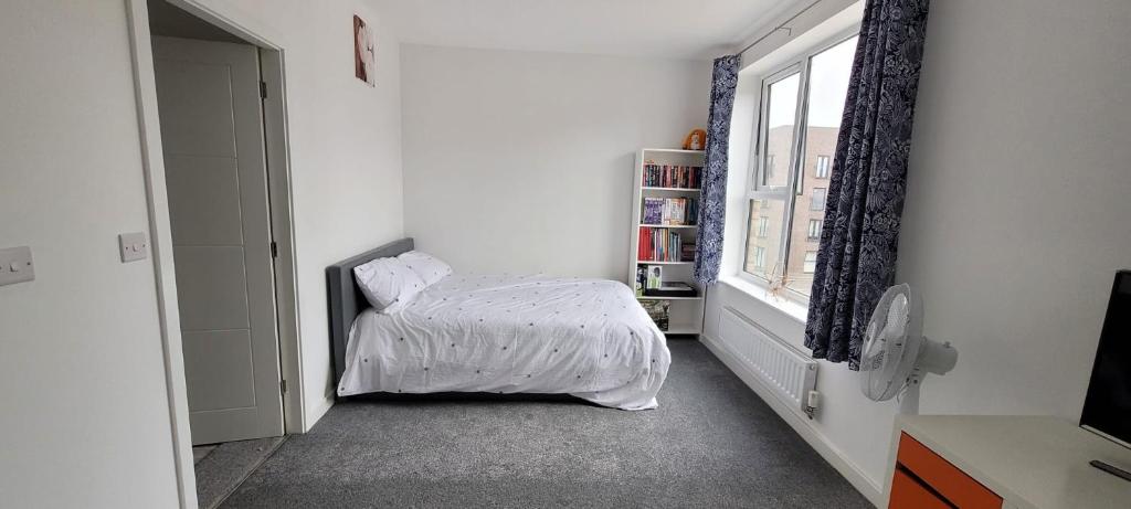 ein Schlafzimmer mit einem Bett mit einer weißen Bettdecke und einem Fenster in der Unterkunft Stretford Townhouse Bedroom in Manchester