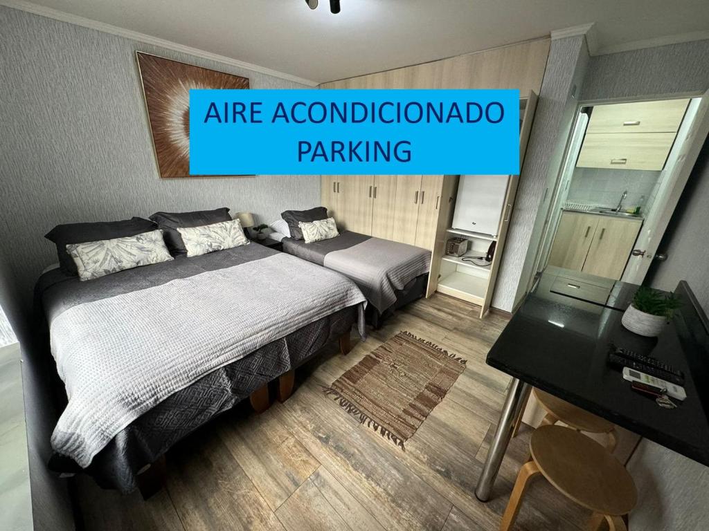a bedroom with two beds and a sign that says air accommodationapo parking at Departamento Studio - Carrera - Factura - Central - Empresas - Parking - Wifi - Aire acondicionado in Chillán