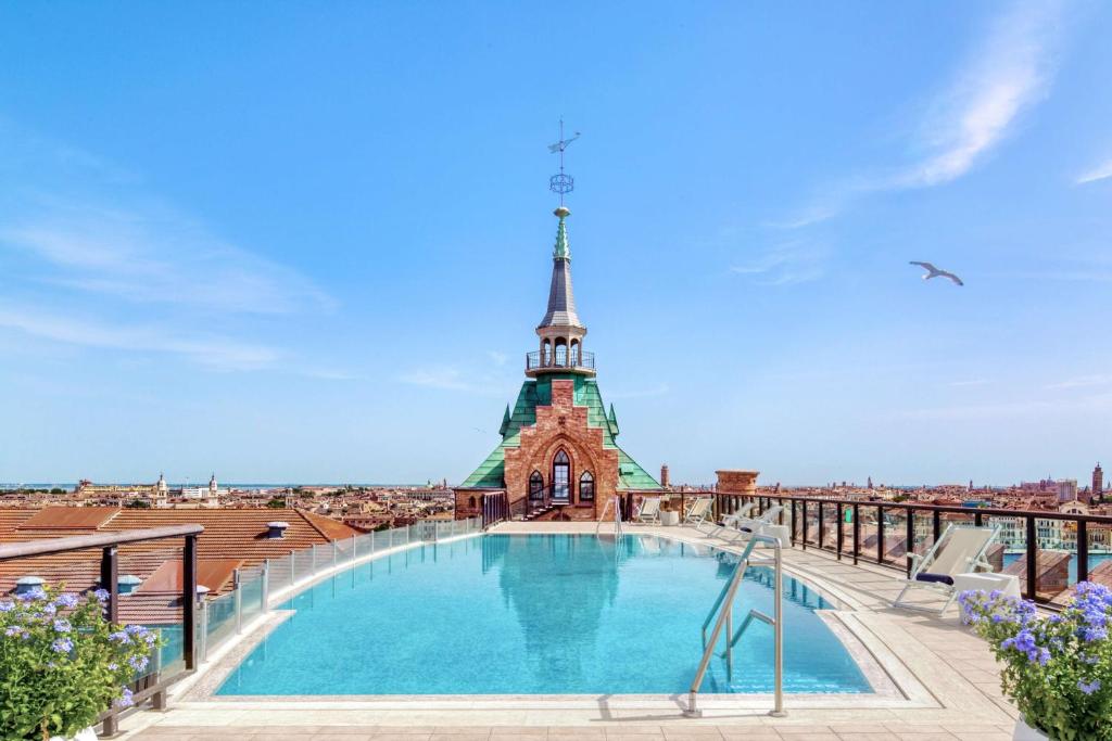 a swimming pool on the roof of a building with a tower at Hilton Molino Stucky Venice in Venice