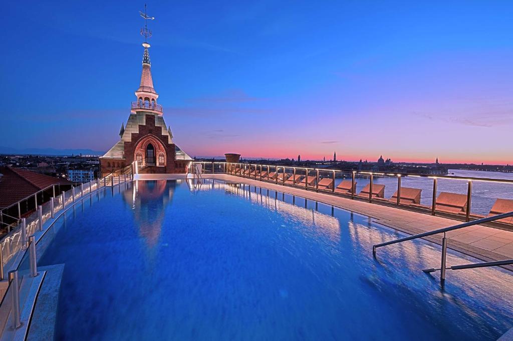 a large swimming pool next to a building with a tower at Hilton Molino Stucky Venice in Venice