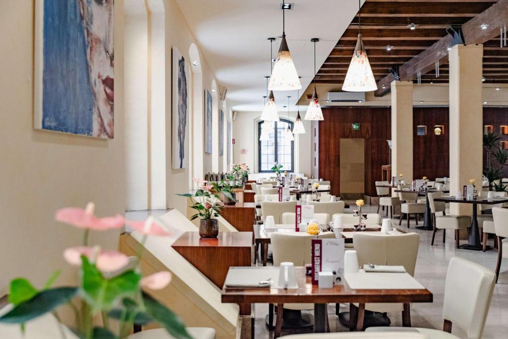 a dining room with tables and chairs and pendant lights at Hilton Molino Stucky Venice in Venice