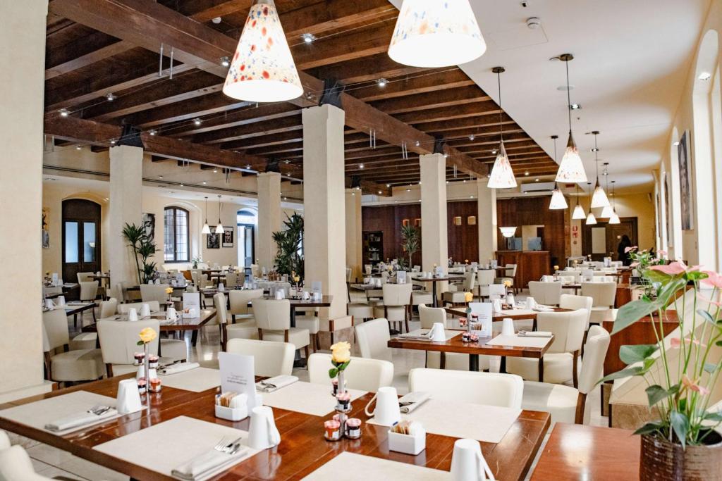 a dining room with tables and chairs and chandeliers at Hilton Molino Stucky Venice in Venice