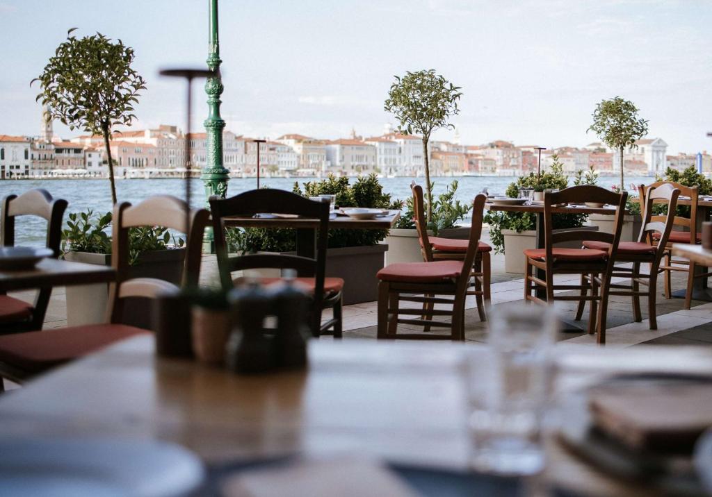 a row of tables and chairs at a restaurant overlooking the water at Hilton Molino Stucky Venice in Venice
