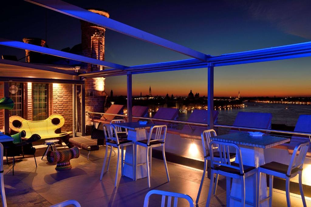 a balcony with tables and chairs and a view of the water at Hilton Molino Stucky Venice in Venice