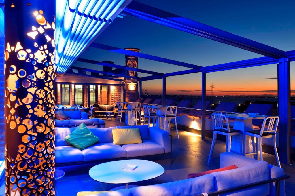 a rooftop bar with couches and tables and a sunset at Hilton Molino Stucky Venice in Venice