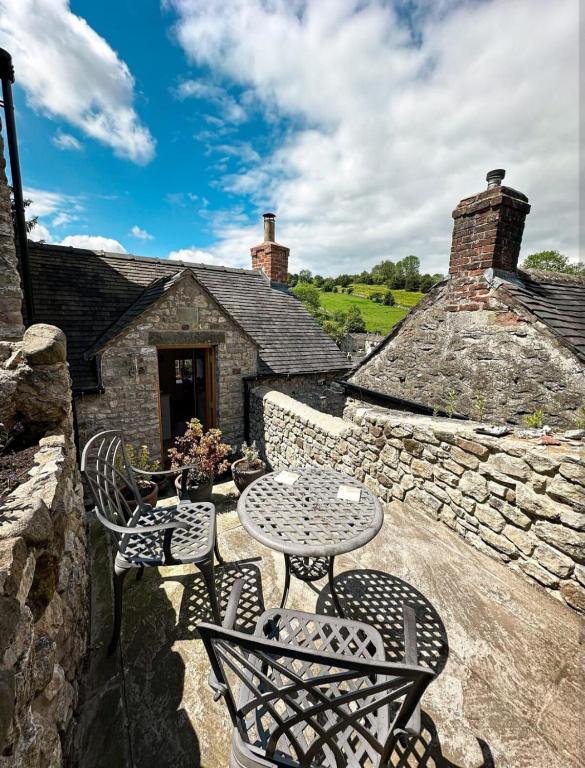 a patio with a table and chairs and a stone building at Loft cottage in Bonsall