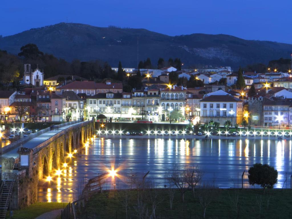 Una ciudad de noche con luces en el agua en Arc My Otel, en Ponte de Lima