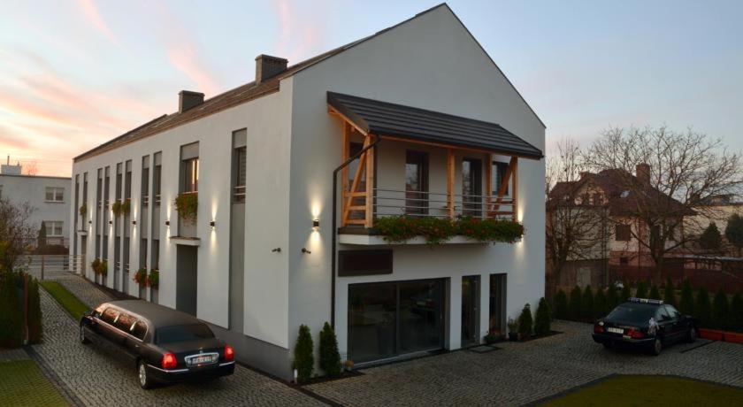 a white house with two cars parked in front of it at VILLA VIP POKOJE pracownicze in Gniezno