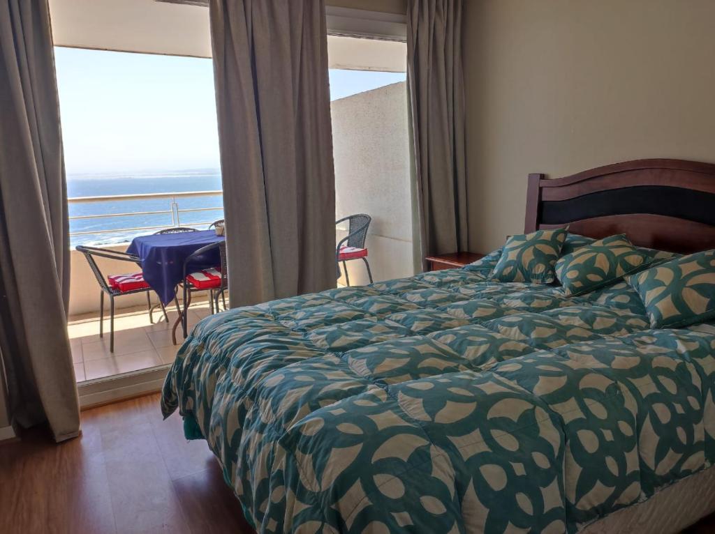a bedroom with a bed and a balcony with a table at VISTAMAR COSTALILENES CONCON in Concón