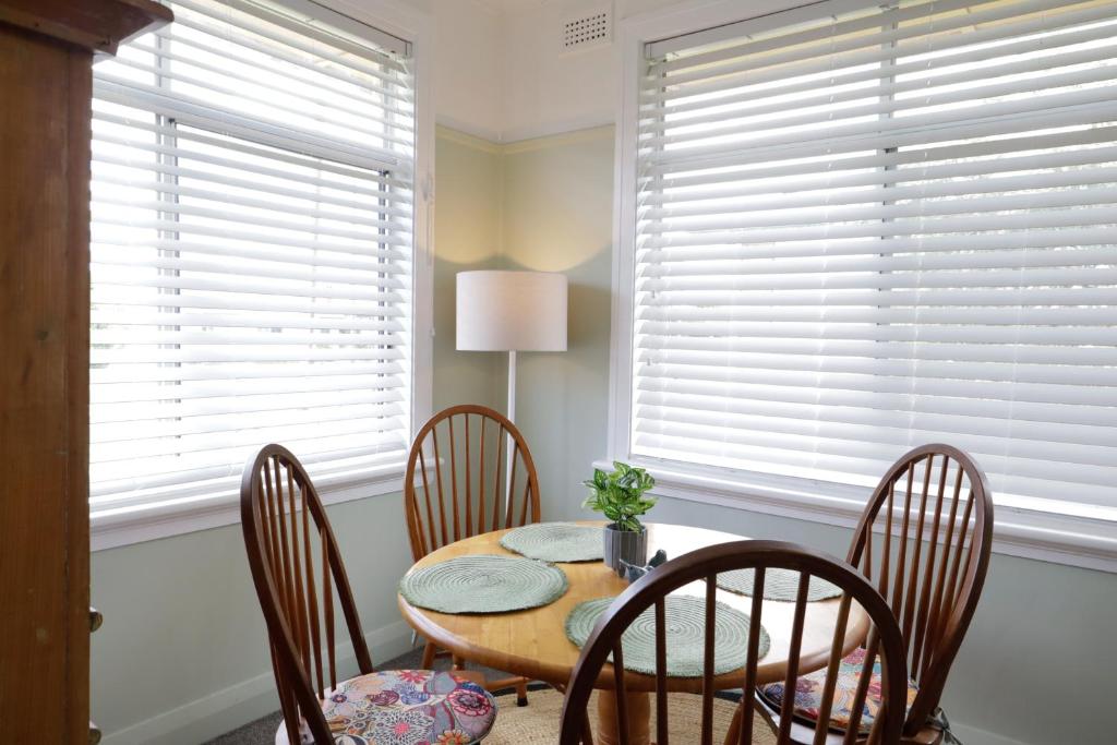 a dining room with a table and chairs and windows at Cosy Sun-Filled Cottage in Tenterfield