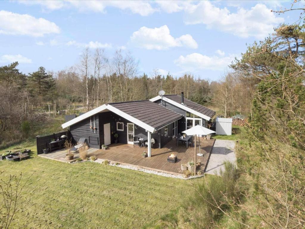 ein kleines Haus mit einer Holzterrasse auf einem Feld in der Unterkunft Tranquil Haven in Lyngsa - By Traum Ferienwohnungen in Sæby