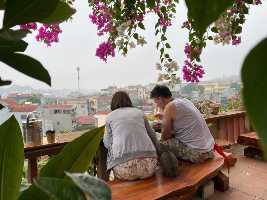 a man and woman sitting on a bench eating food at Kha Bản Homestay in Cao Bằng