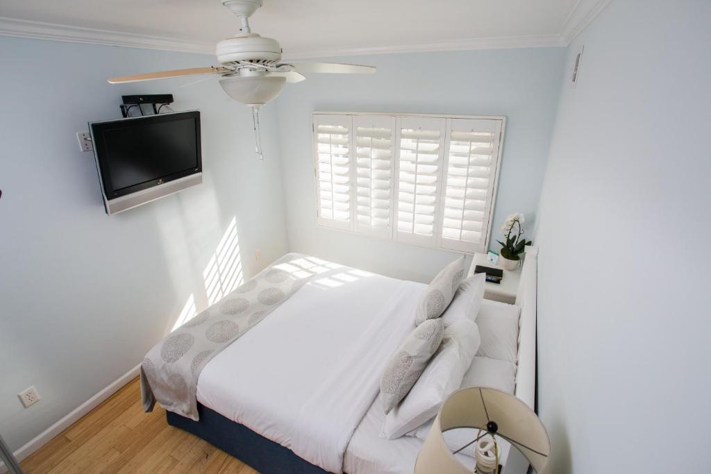 a white bedroom with a bed and a flat screen tv at Venice on the Beach Hotel in Los Angeles