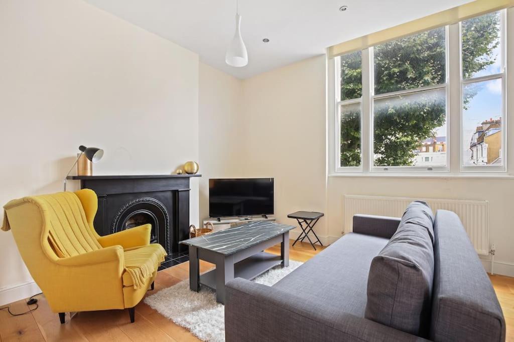 a living room with a couch and a fireplace at Stylish 1-Bed Flat in Prime Kensington Location in London