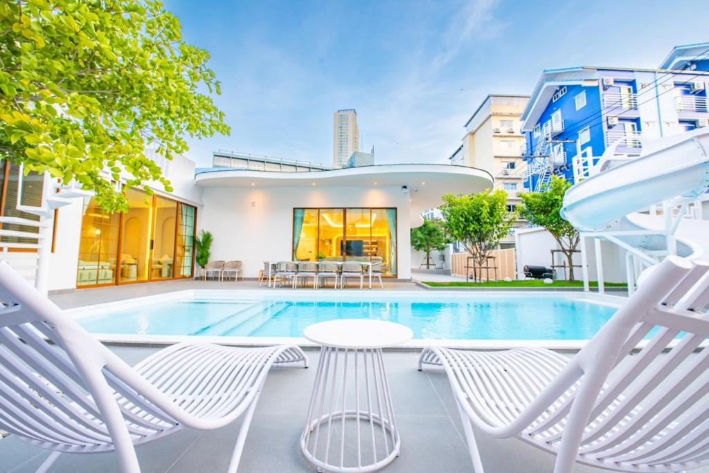 a house with a swimming pool and two lawn chairs at Paco Villa Pattaya in Jomtien Beach