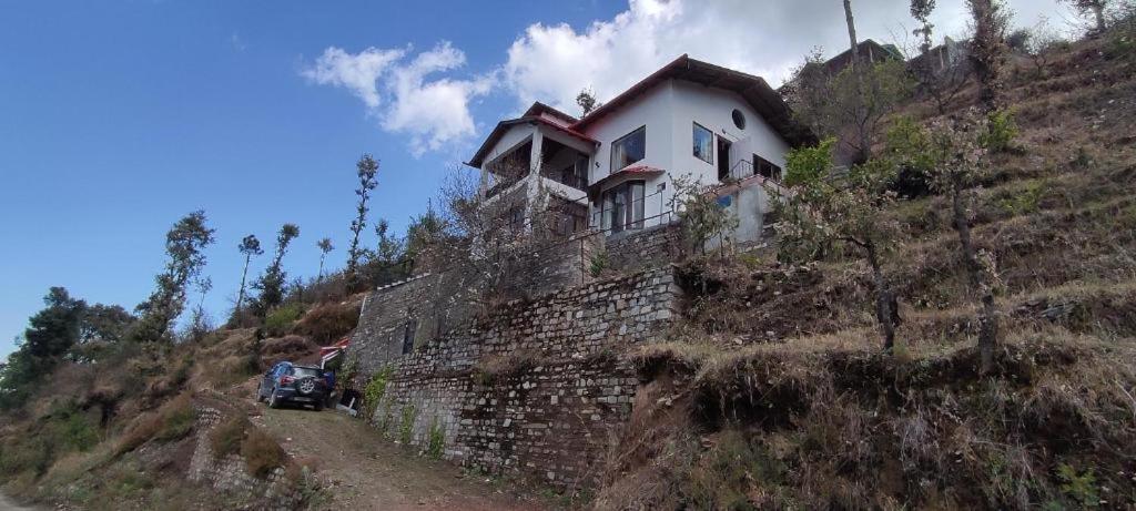 a house on top of a stone wall on a hill at Katie's Abode, Hartola in Rāmgarh