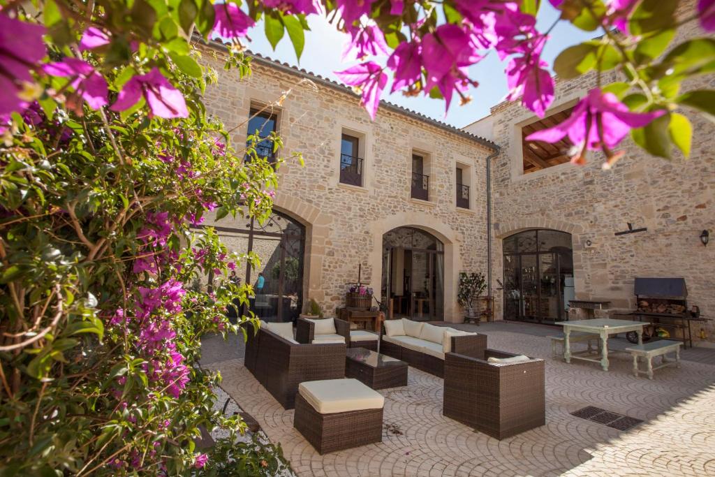- un bâtiment avec une terrasse ornée de fleurs violettes dans l'établissement L'Escampe, à Saturargues